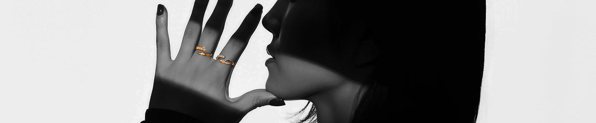 ゴールドのリングを着けた手を口元にかざす女性の横顔（モノクロ）