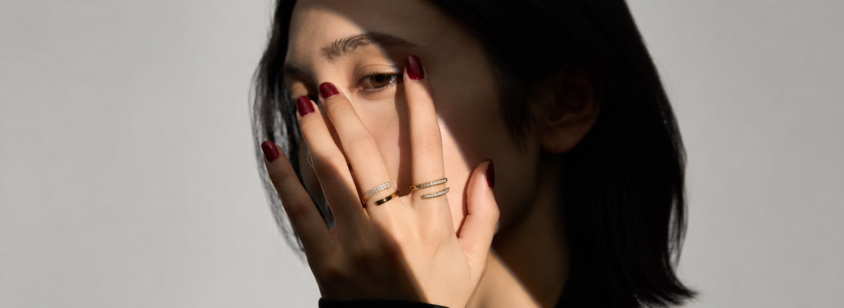 ダイヤモンドのリングを重ねづけした手で口元を覆う女性